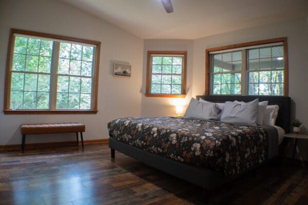 A bedroom with two windows and a bed in it