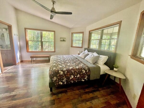 A bedroom with hard wood floors and a large bed.