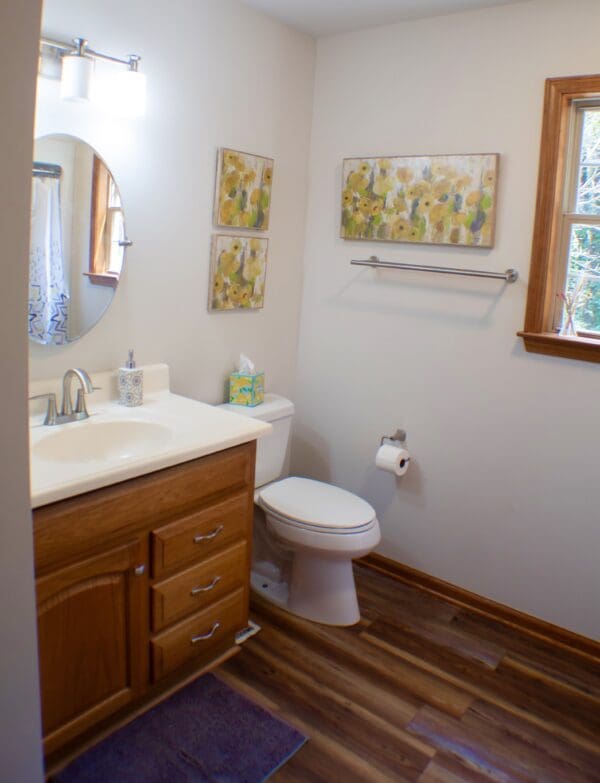 A bathroom with wood floors and white walls.