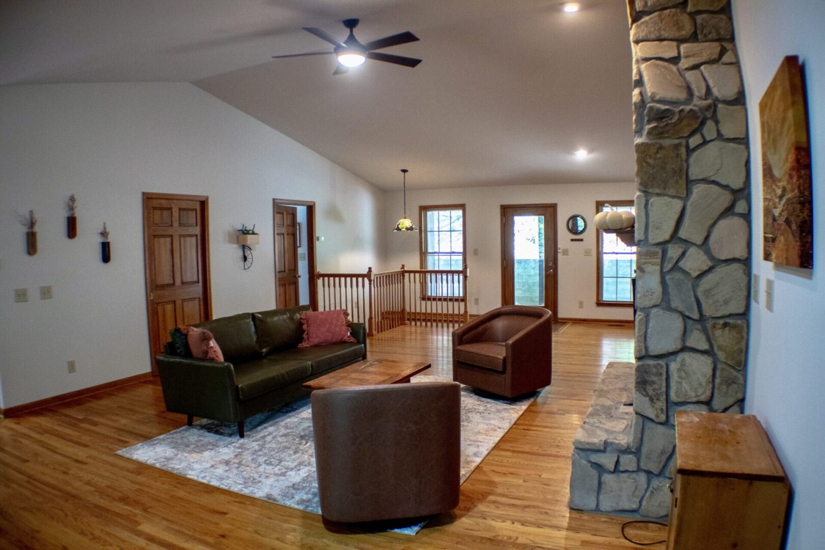 A living room with hard wood floors and stone walls.